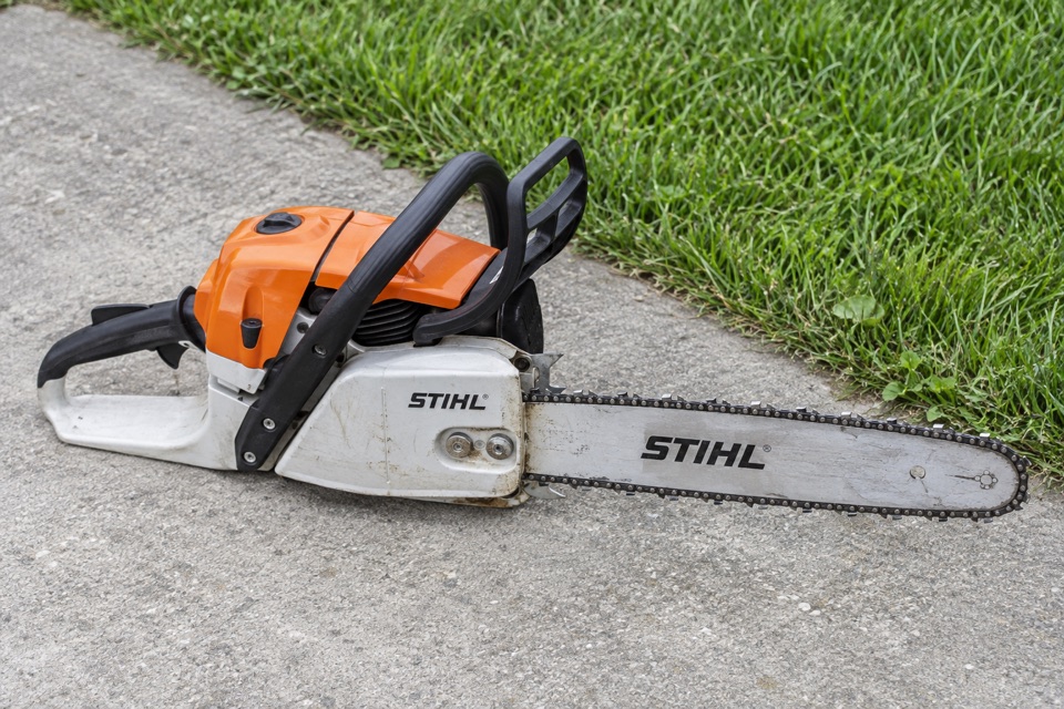 AI illustration of a STIHL chainsaw on concrete beside grass