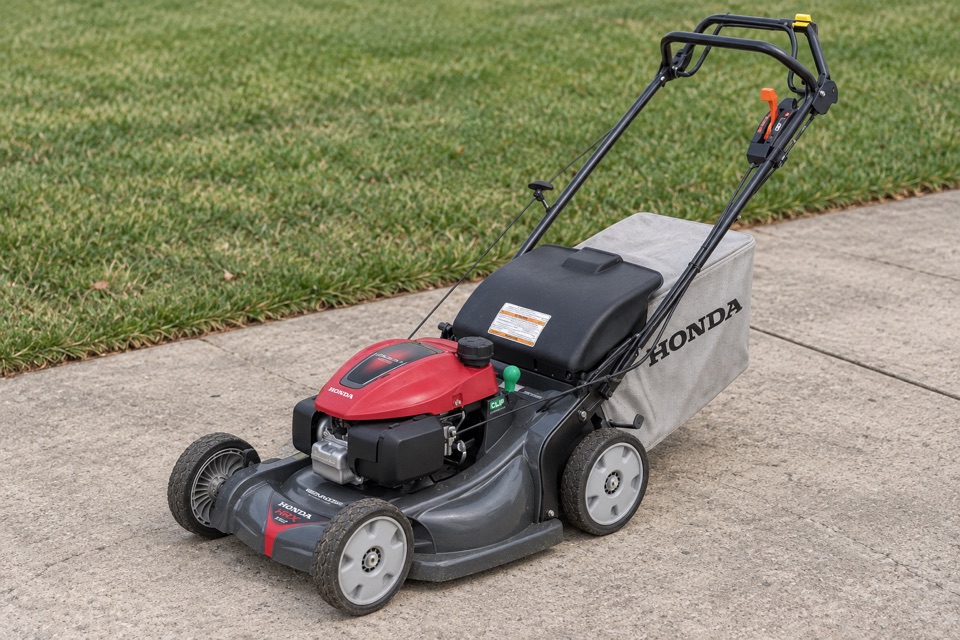 AI illustration of a Honda walk-behind mower on concrete beside grass